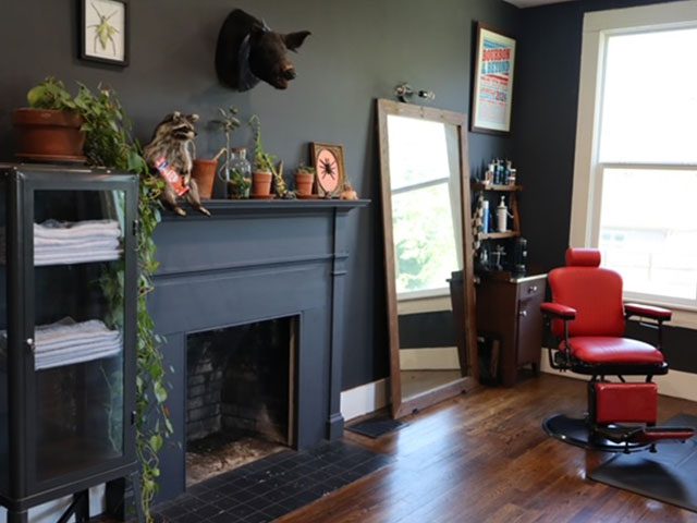 Home with green walls, a fireplace and a red barber chair in the corner next to a window.